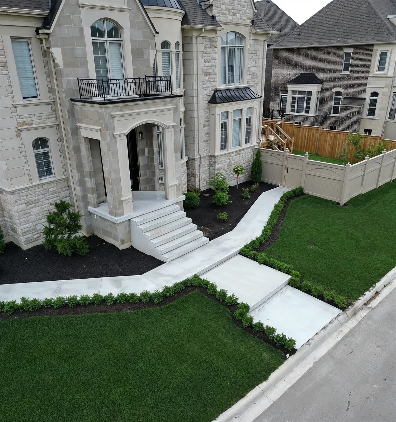 Stone home with a new concrete front walkway, stone steps, fresh sod and boxwood hedges by J Group Renovations