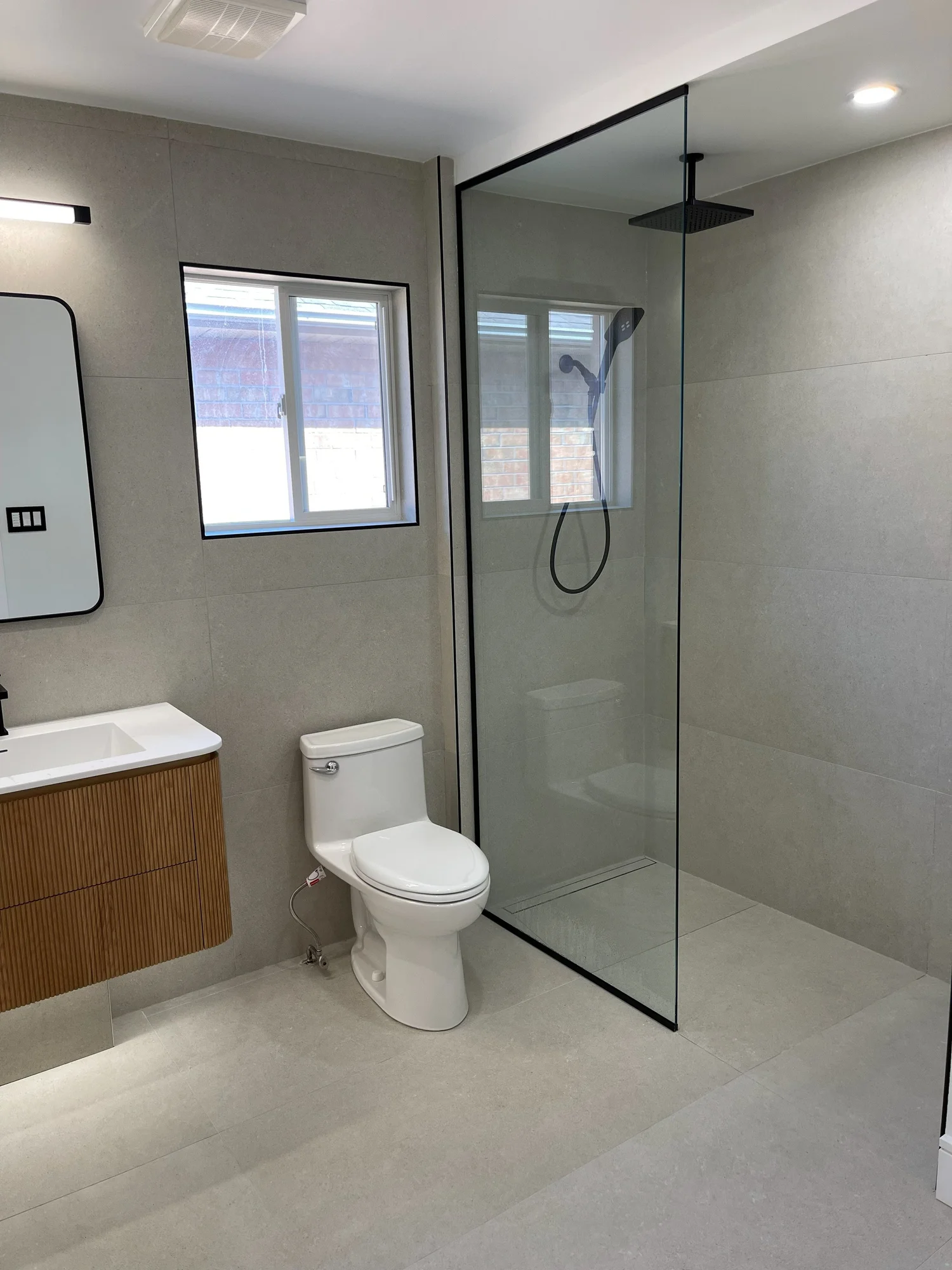 Vaughan bathroom after the renovation, with a curbless walk-in shower, glass panel and floating wood vanity