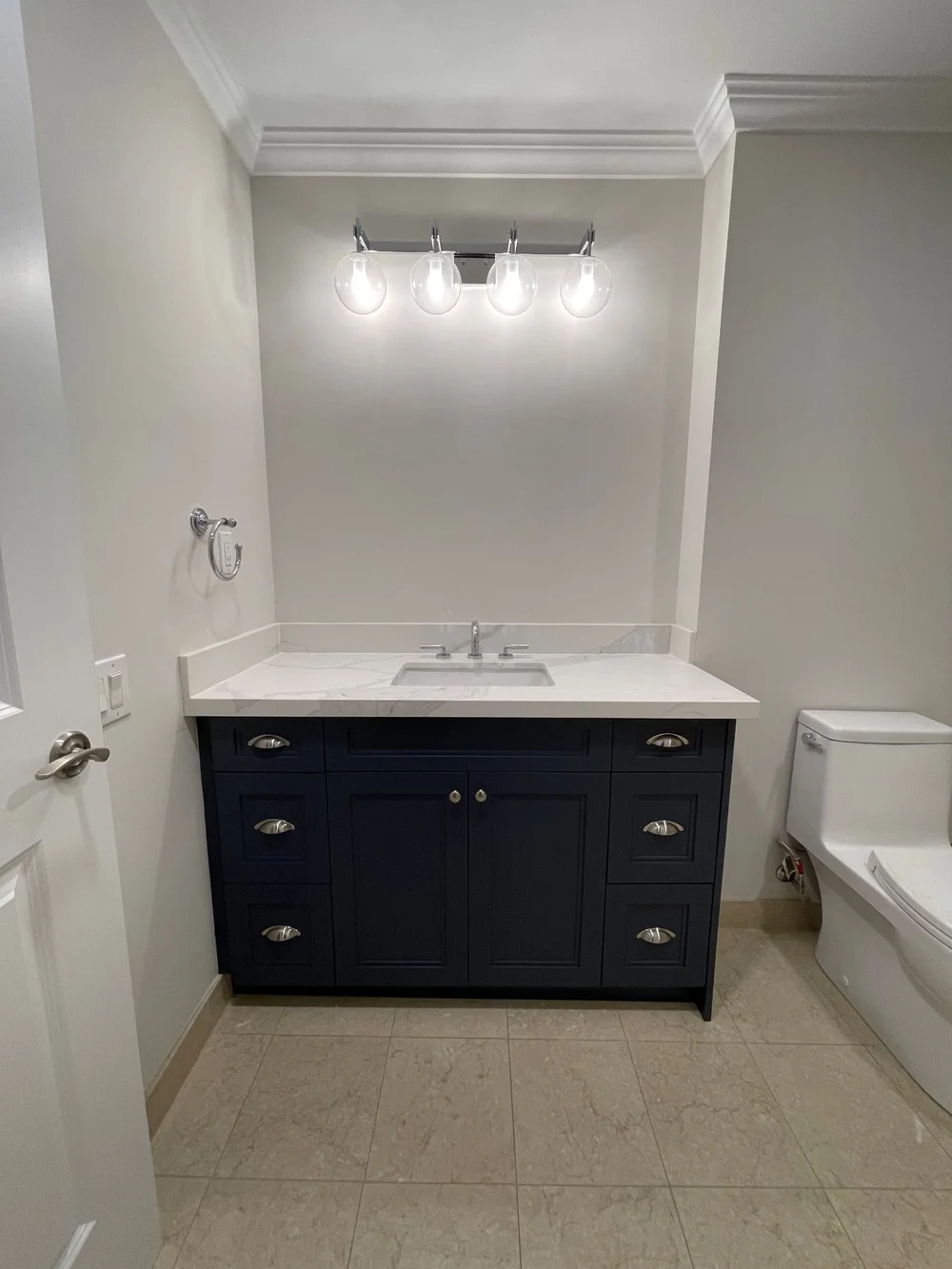 Renovated Etobicoke bathroom with a navy shaker vanity, white counter and new light fixture