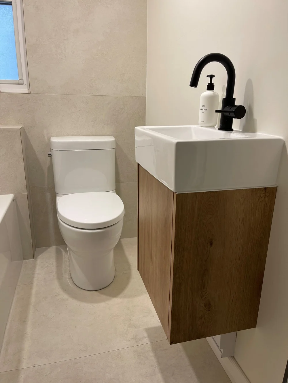 Compact wood floating vanity with a matte black faucet in a Leslieville bathroom