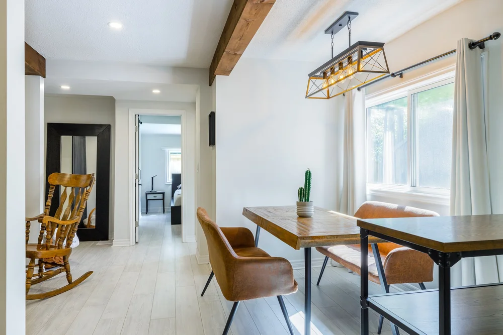 Renovated dining area with modern light fixture and wood beams