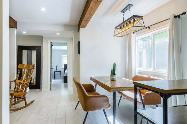 Renovated dining area with a modern light fixture and wood beams