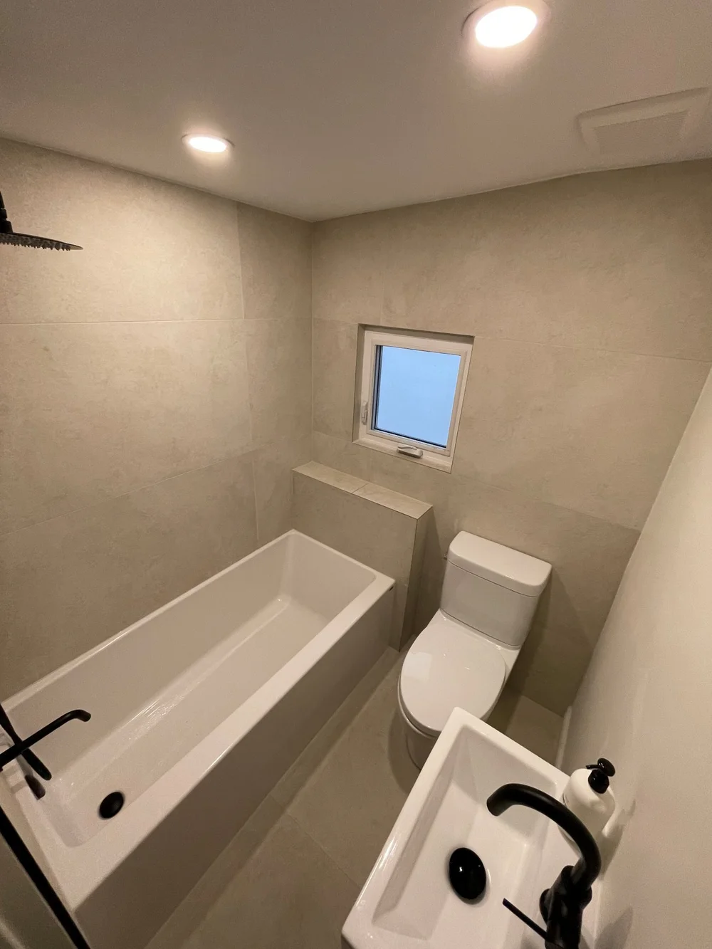 Renovated Leslieville bathroom with a new tub, large-format tile and a window