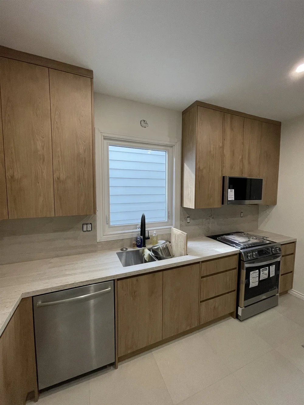 Leslieville kitchen with wood-grain cabinets, quartz counters and a window over the sink