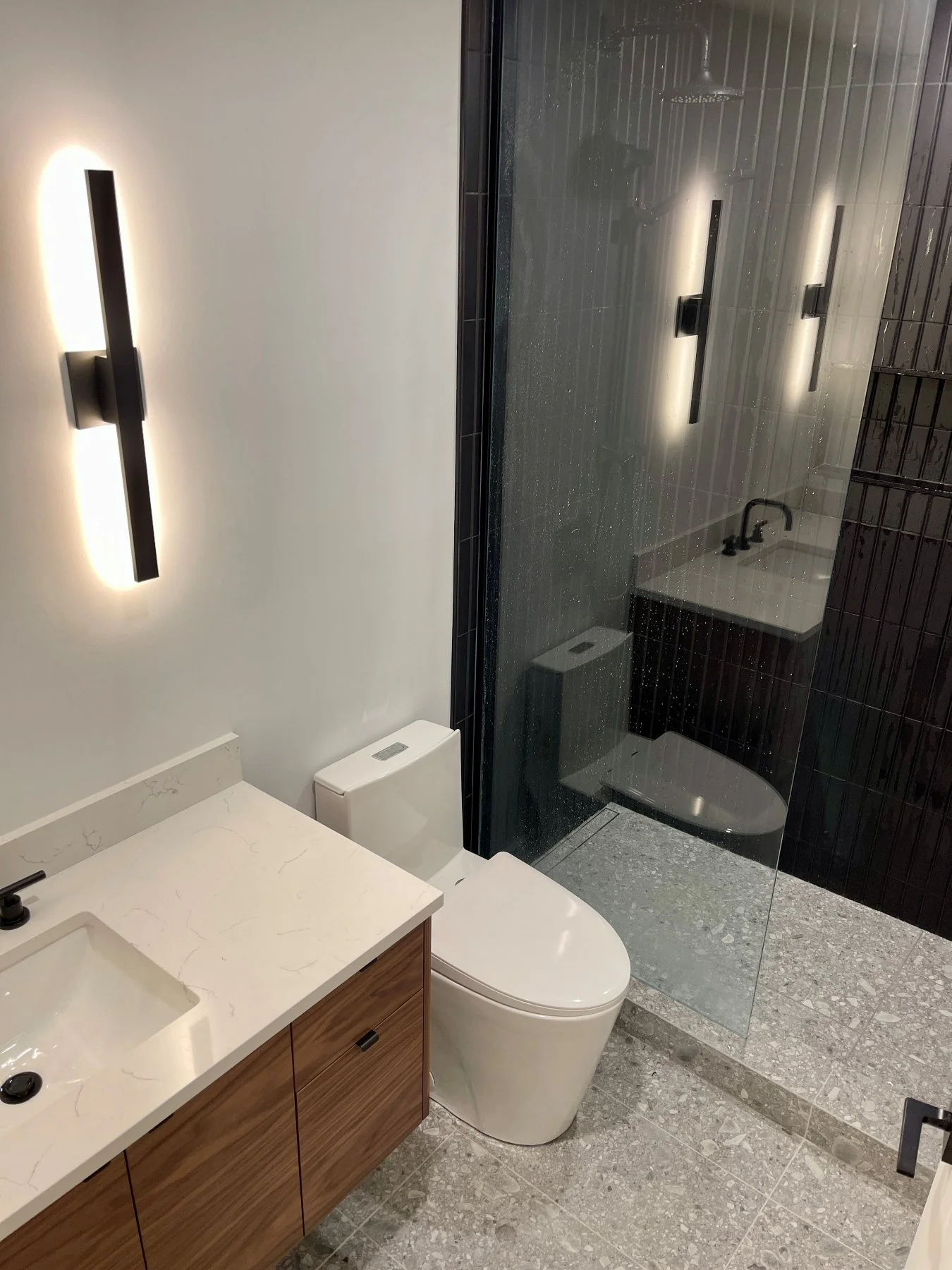 New walk-in shower with black wall tile and glass in the renovated Distillery District condo bathroom
