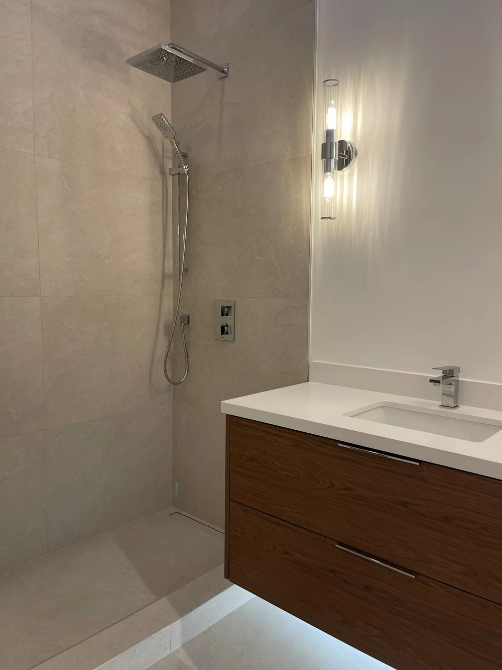 Walnut floating vanity with LED underlighting beside the new shower at Toy Factory Lofts