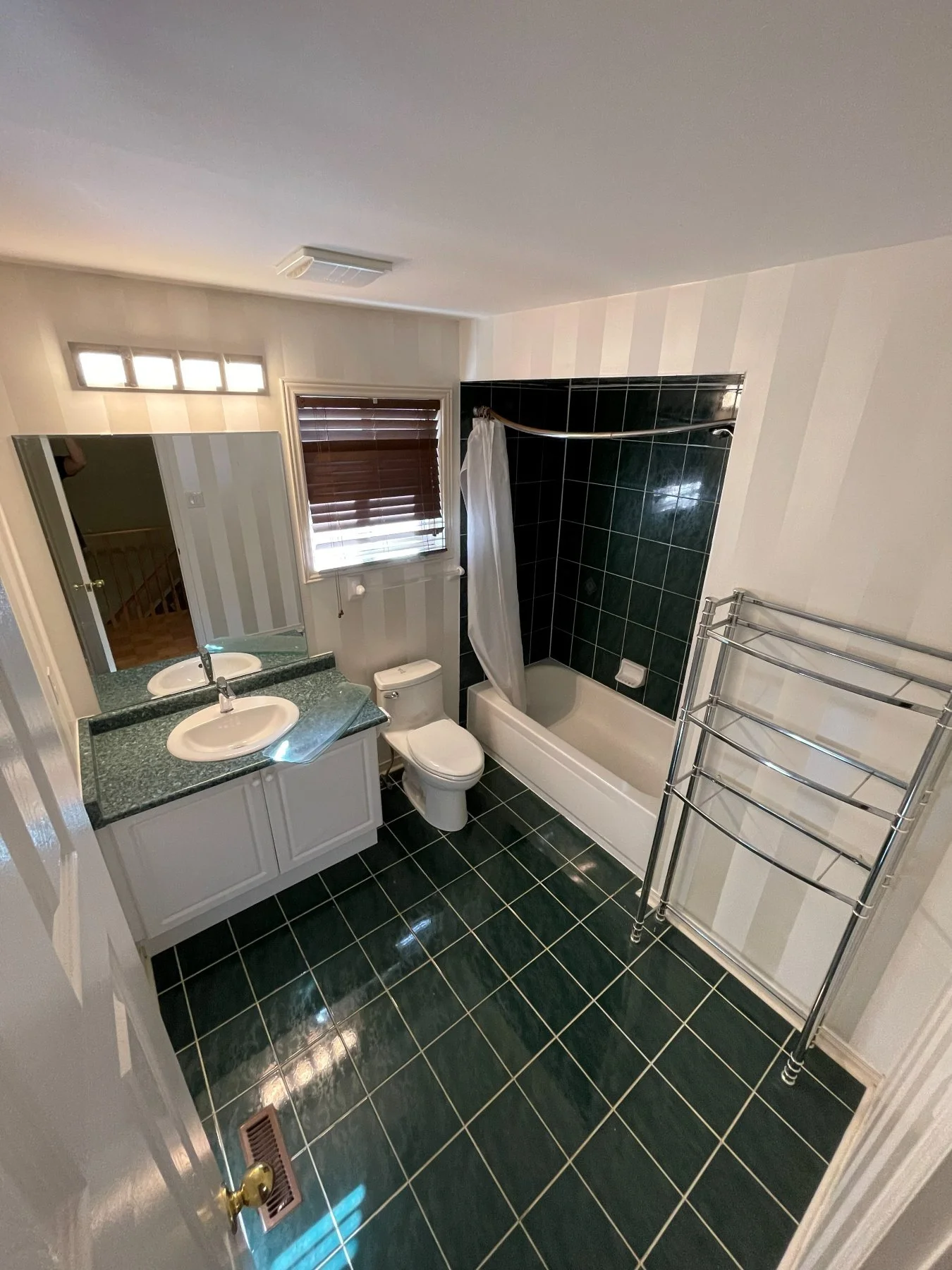 Vaughan bathroom before the renovation, with dark green floor tile, a tub and a dated vanity