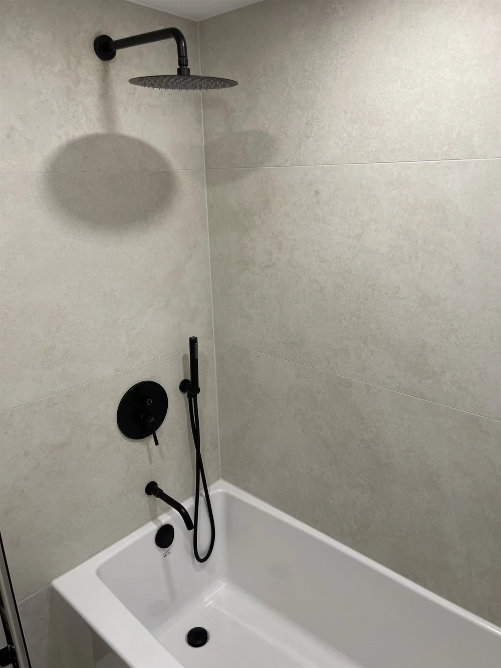 Tub and shower combination with large-format tile and a matte black rain shower