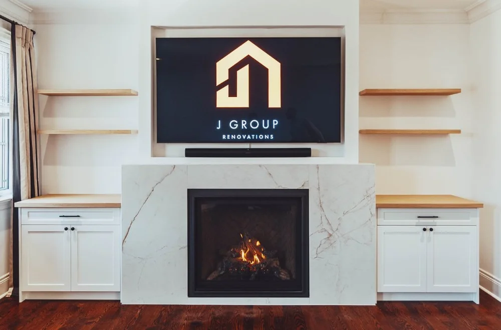 TV wall with built-in storage and floating shelves around a marble fireplace