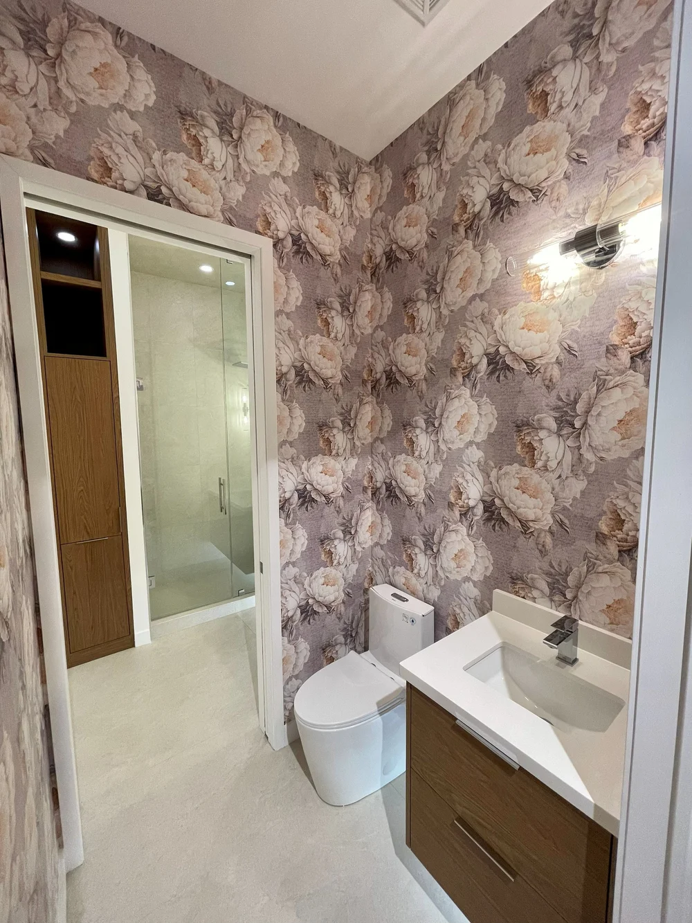 Powder room with floral feature wallpaper and a floating vanity