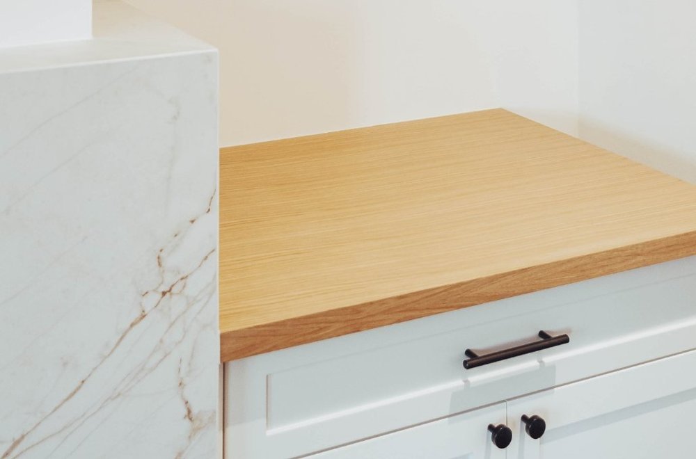 Custom cabinet with a wood top beside the marble fireplace