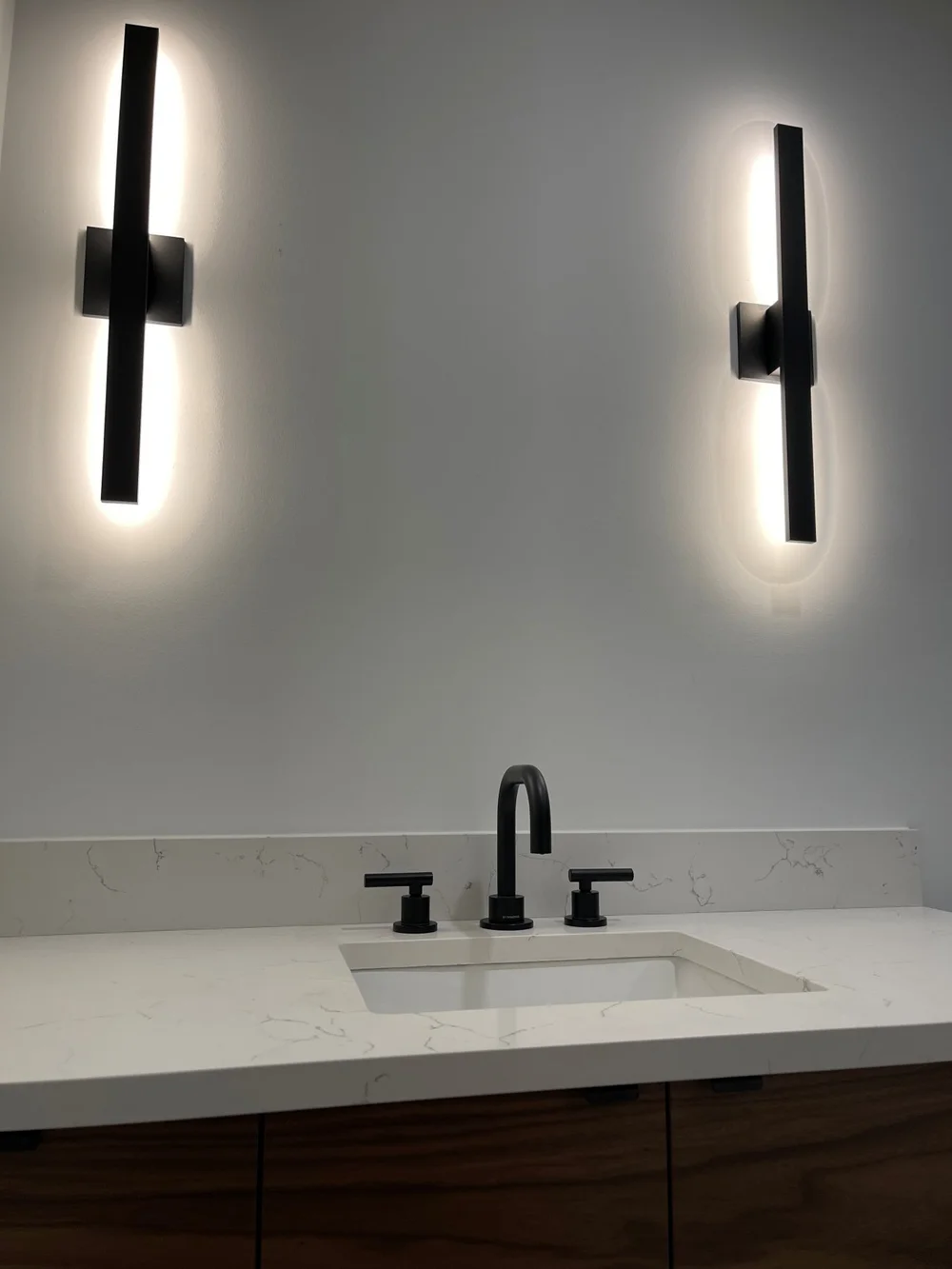 LED wall sconces and matte black faucet over the new vanity