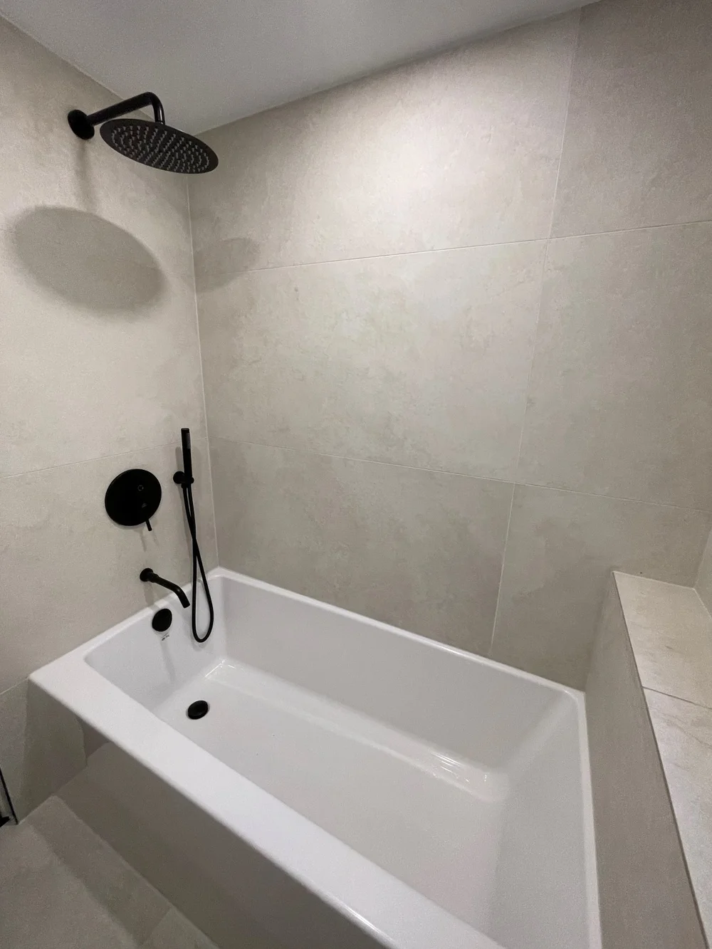 Rain shower head and matte black tub fixtures in a Leslieville bathroom