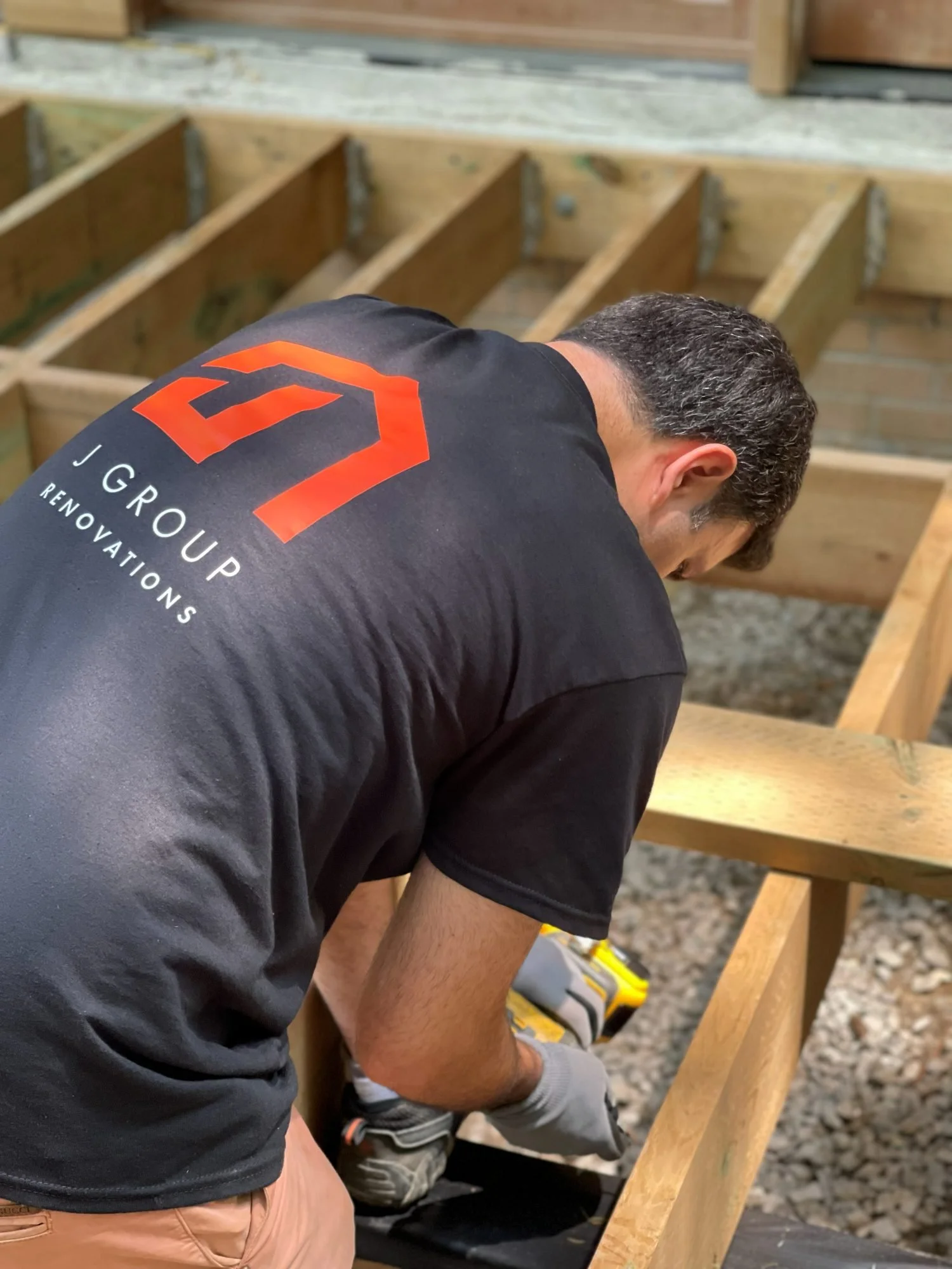 J Group Renovations crew member in a company shirt framing a new deck in Hoggs Hollow, Toronto
