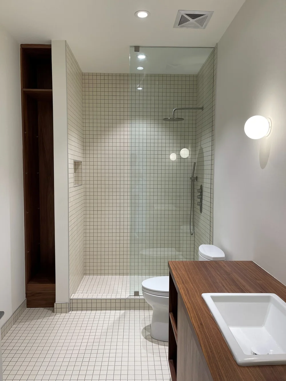 Mosaic tile shower with walnut vanity and built-in shelving