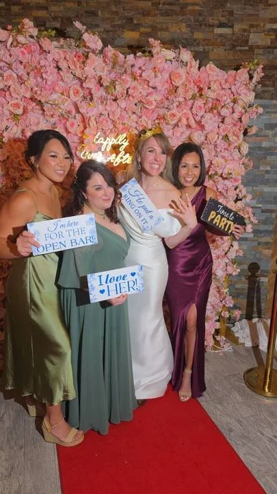 Guests in front of the pink 5D flower wall with a neon sign