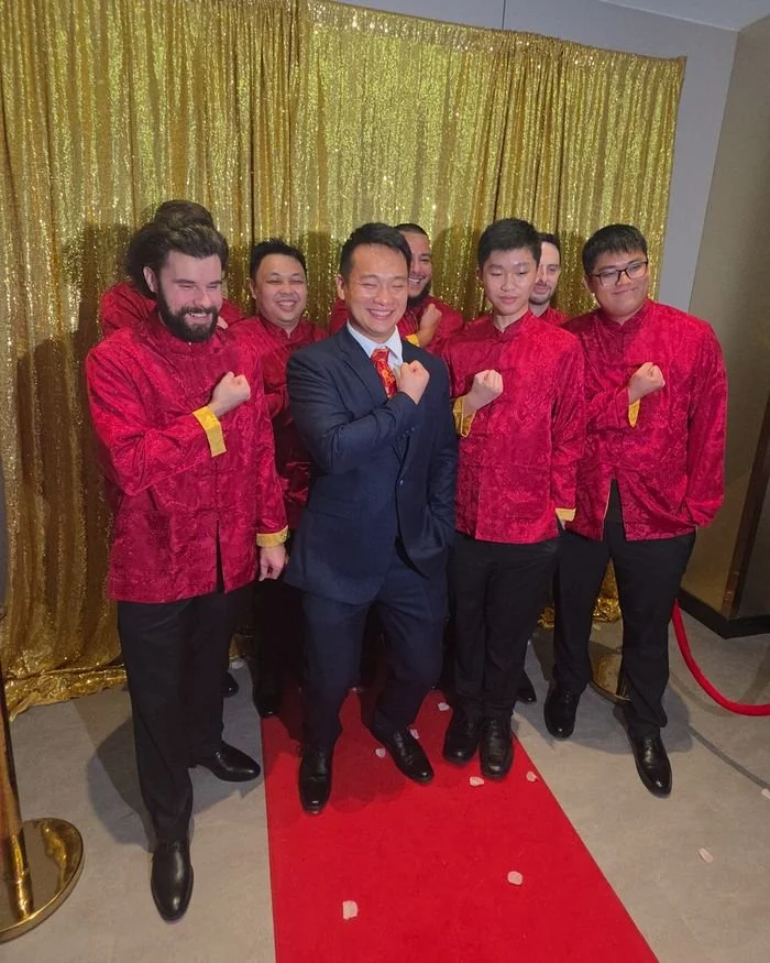 Groomsmen posing in front of the gold sequin backdrop