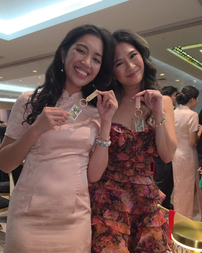 Two wedding guests smiling and holding up their custom photo keychains