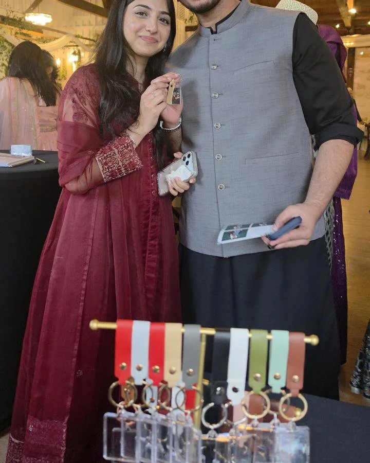 Two wedding guests holding their photo keychain next to the keychain display