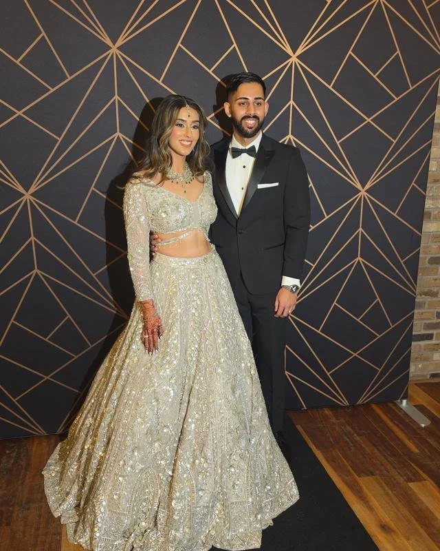 A couple in front of the black and gold fabric backdrop