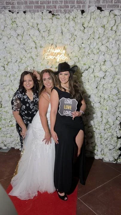 Guests in front of the white 5D flower wall with a neon sign