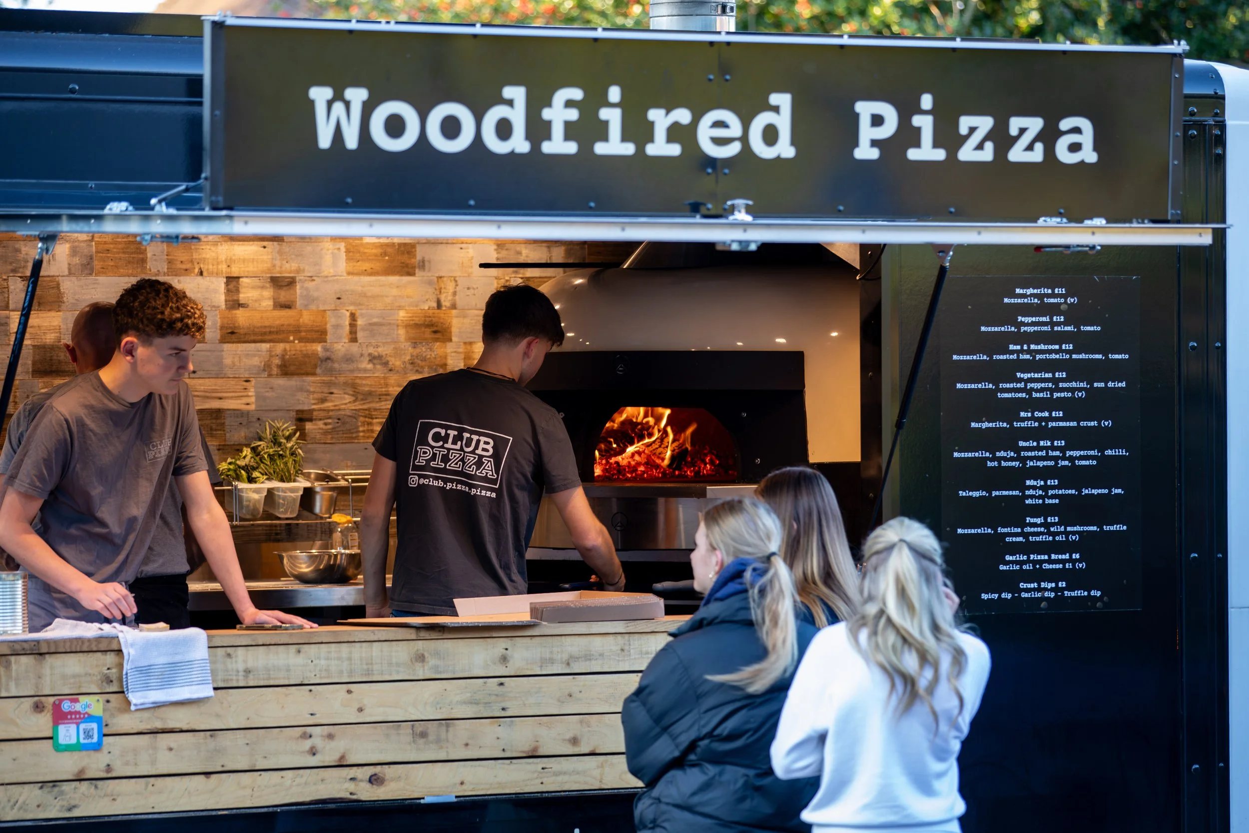 Customers checking menu at Club Pizza van at The Crossways Inn Churt