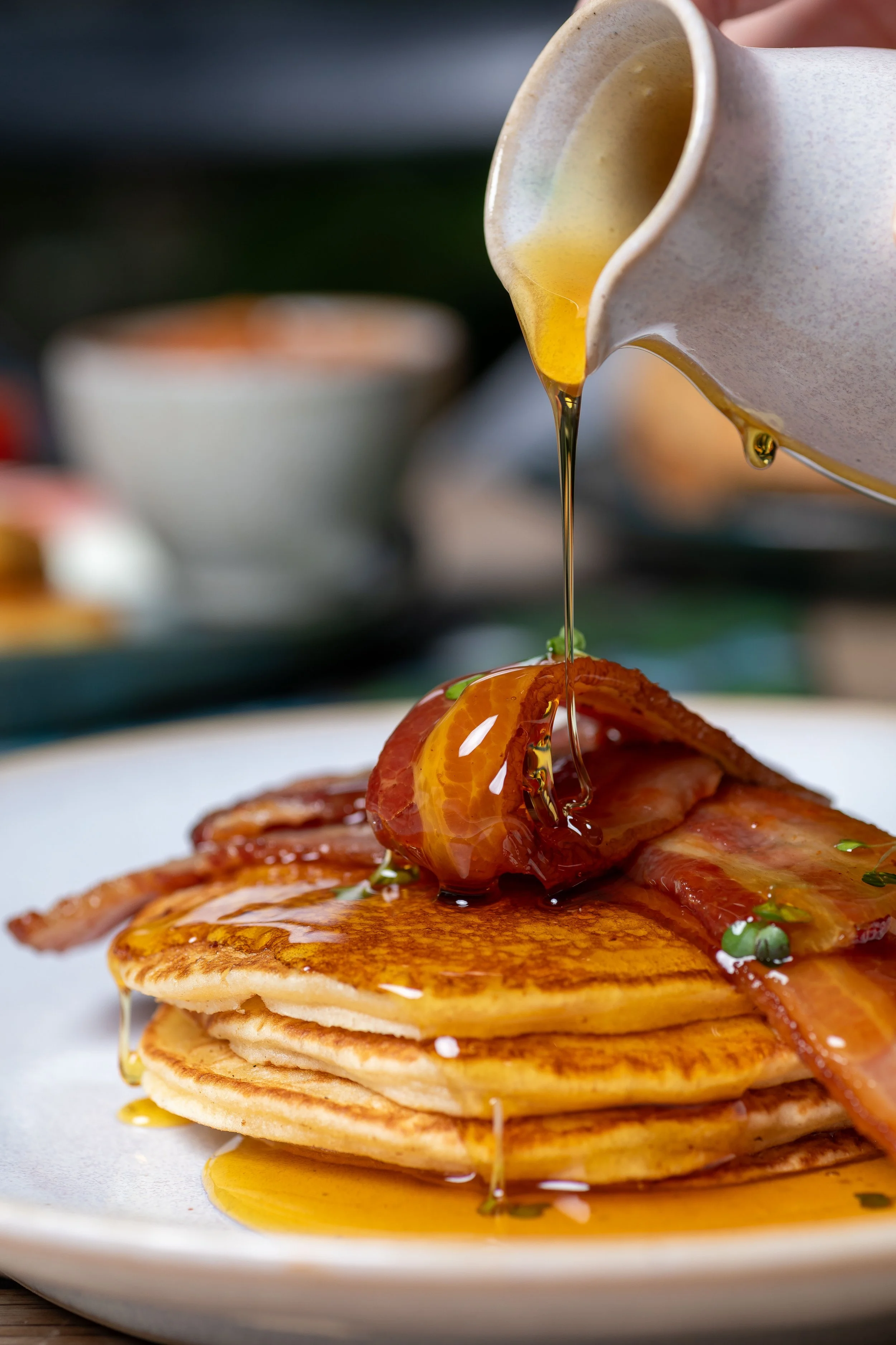 Maple syrup pouring onto panckaes with bacon at The Kiln Café located in Grayshott Pottery
