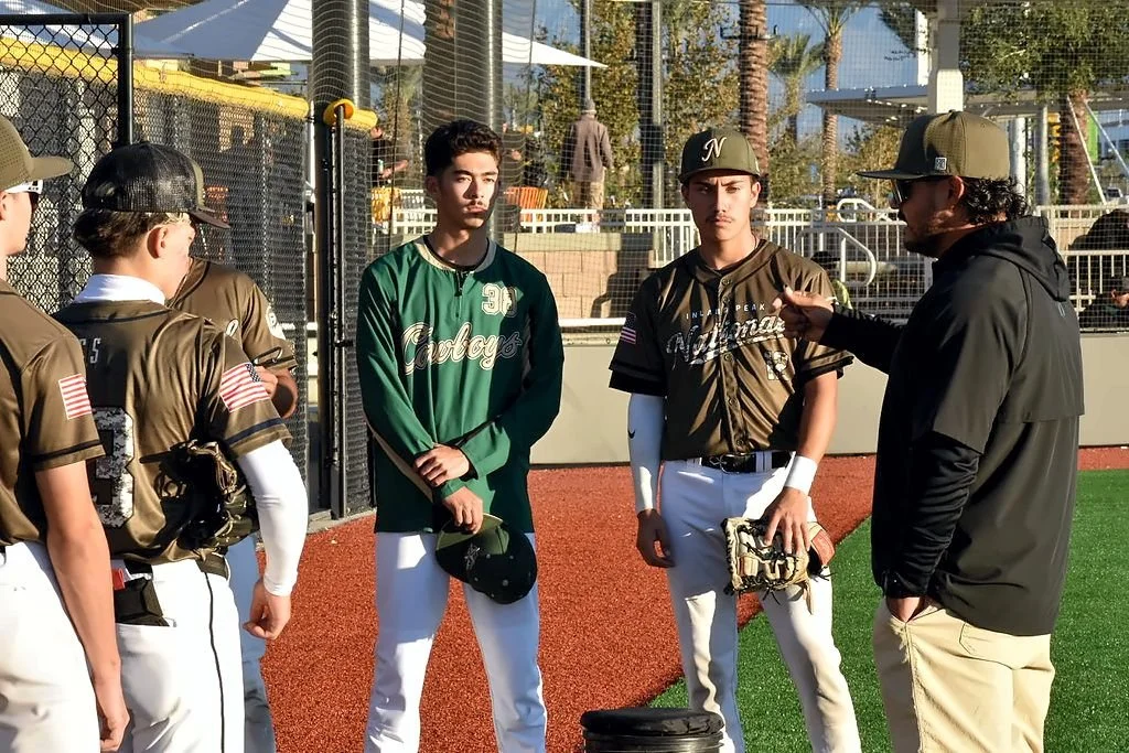 Inland Peak Baseball players and coach in a team huddle