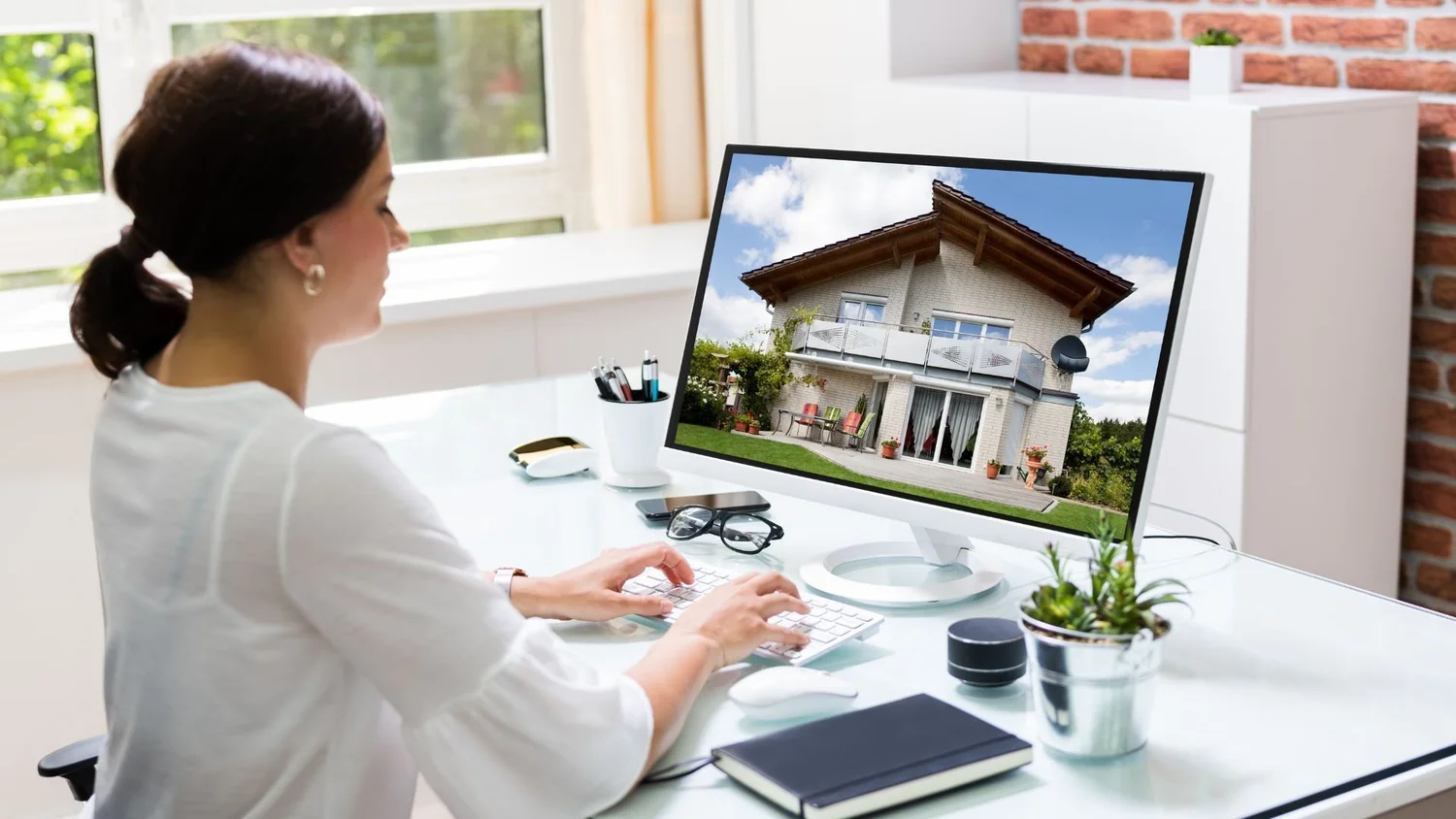 Property manager marketing a rental home online with a listing on her computer screen
