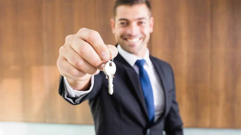 Smiling property manager holding out the keys to a rental home