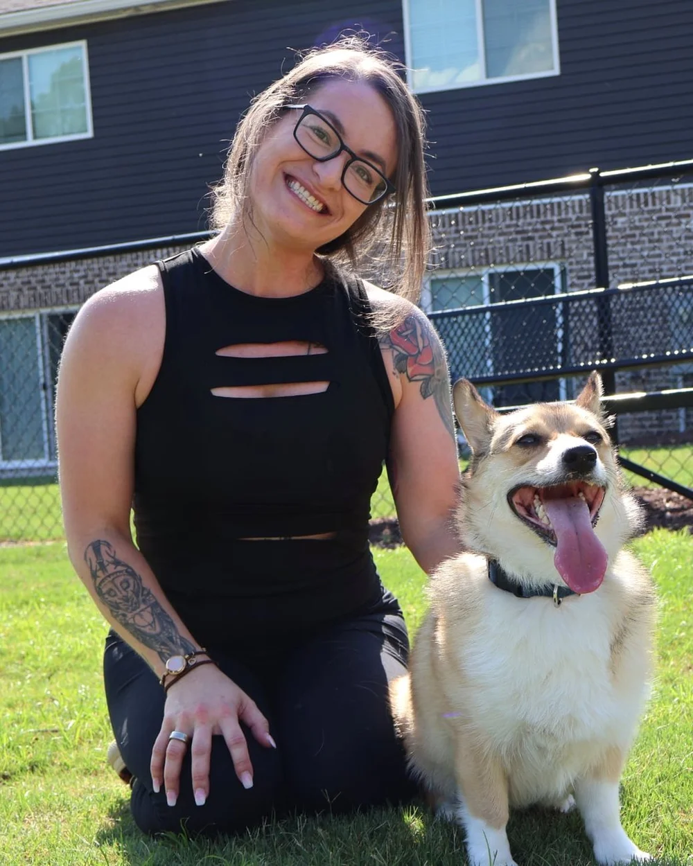 Kristen Spang kneeling in the grass with her corgi