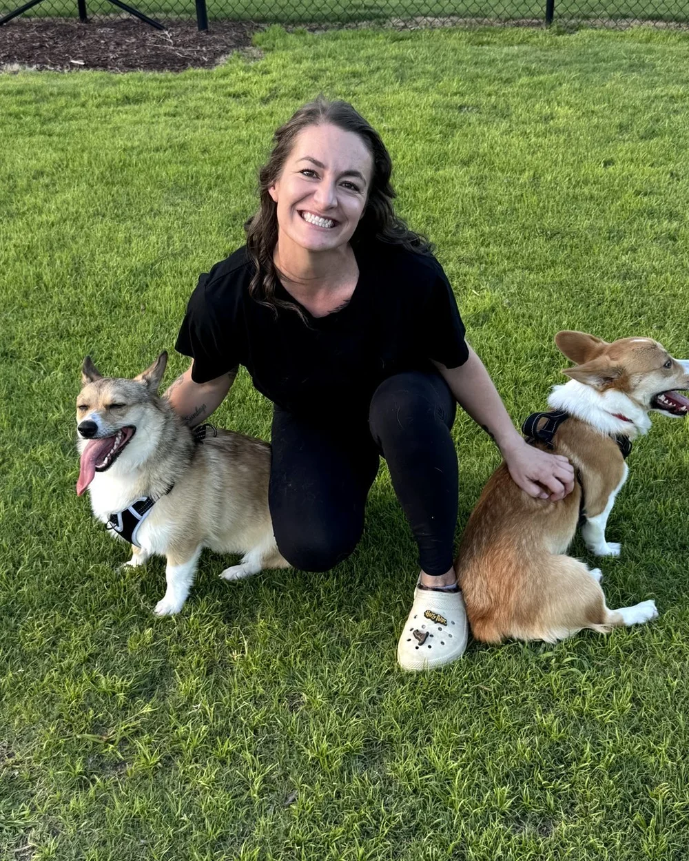 Kristen Spang sitting in the grass with her two corgis