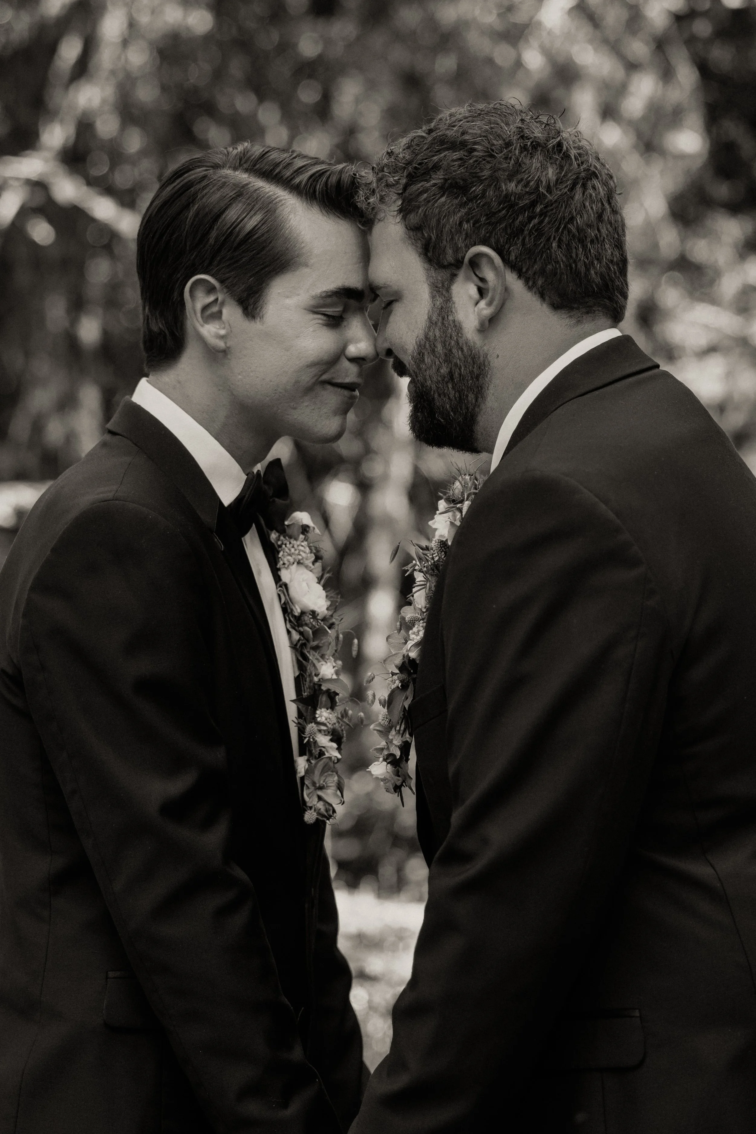 Two grooms forehead to forehead during their Glacier National Park elopement, photographed by Stan Todorov