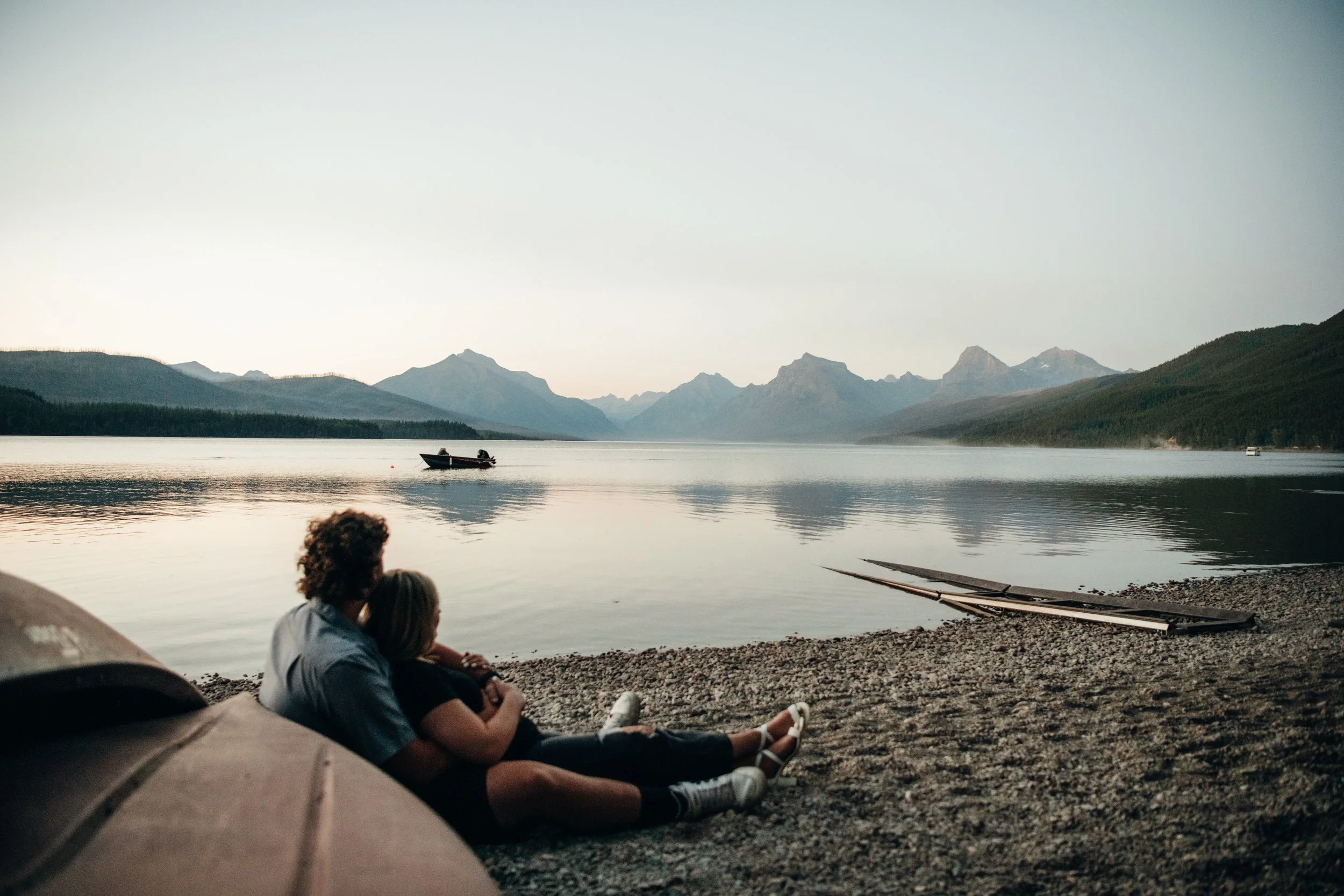 Couple sitting by a lakeshore with mountain views in Montana during an intimate portrait session