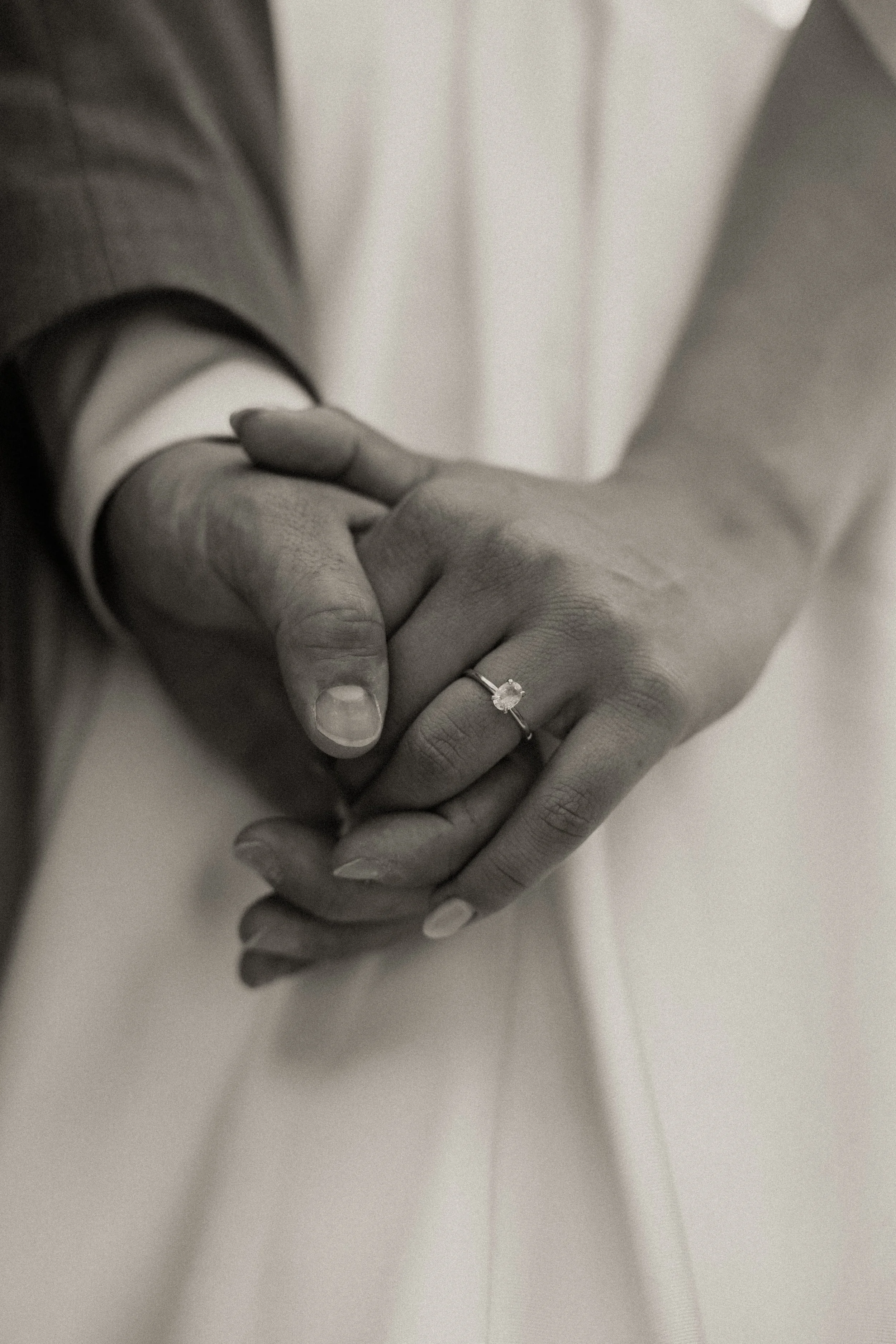 Intimate black and white detail of couple holding hands with wedding rings during Montana elopement