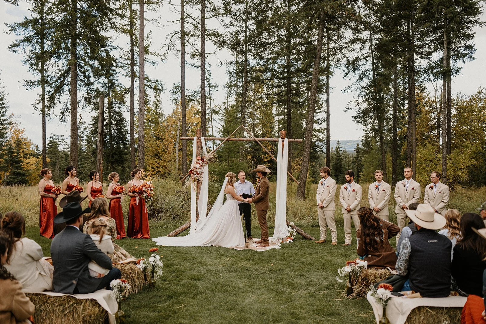 Outdoor wedding ceremony at Jewel Basin Weddings in Kalispell, Montana with a wooden arch and hay bale seating