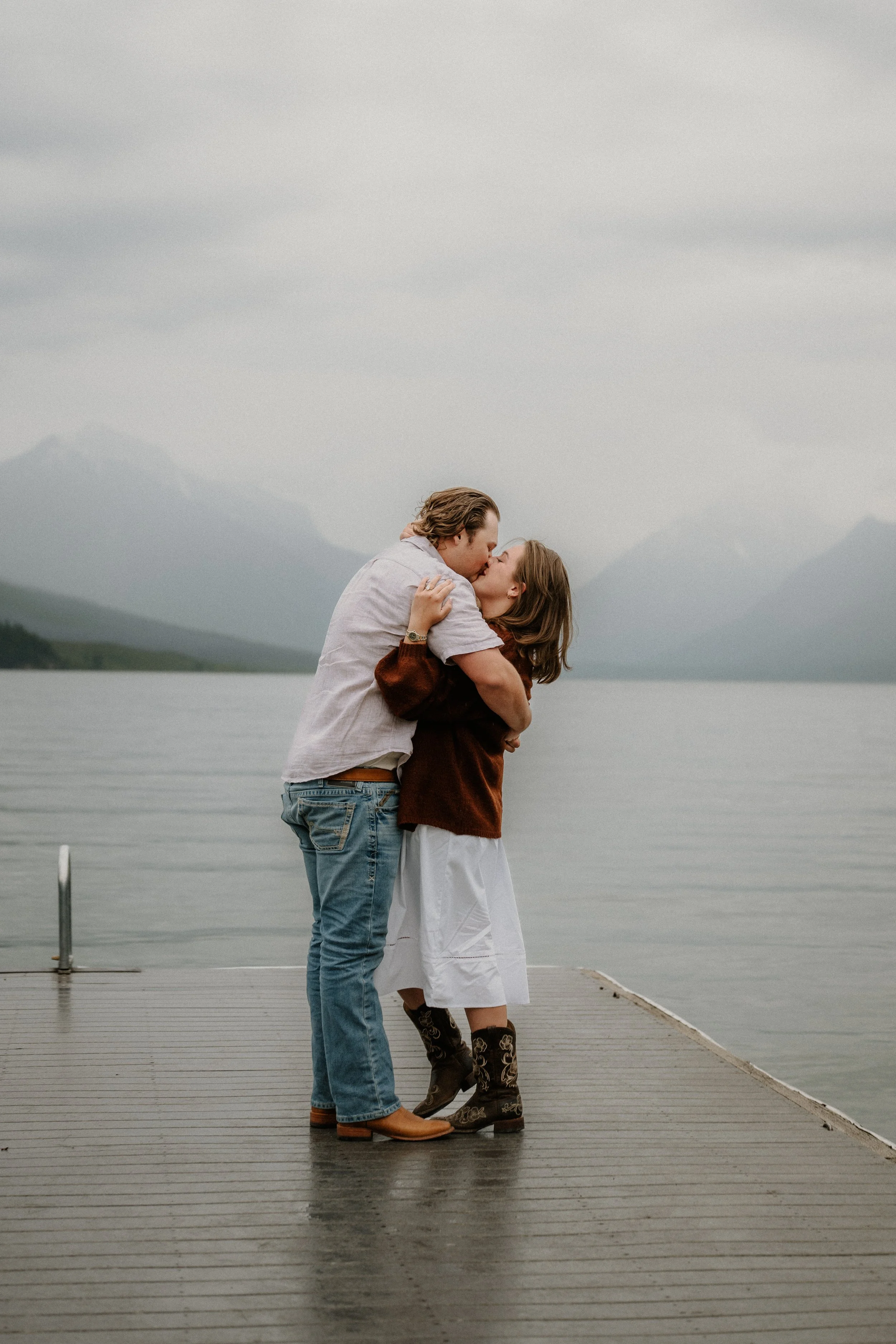 Jenica and Brenden laughing in the rain after getting engaged at Lake McDonald