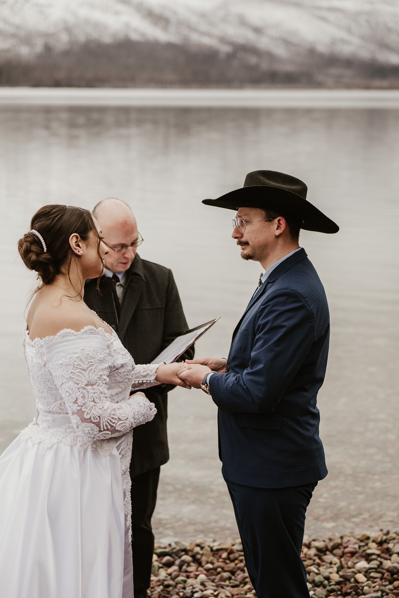 Ian and Rachel's intimate elopement ceremony at the 7-Mile Pullout in Glacier National Park, immediate family gathered around them on the pebbled shore