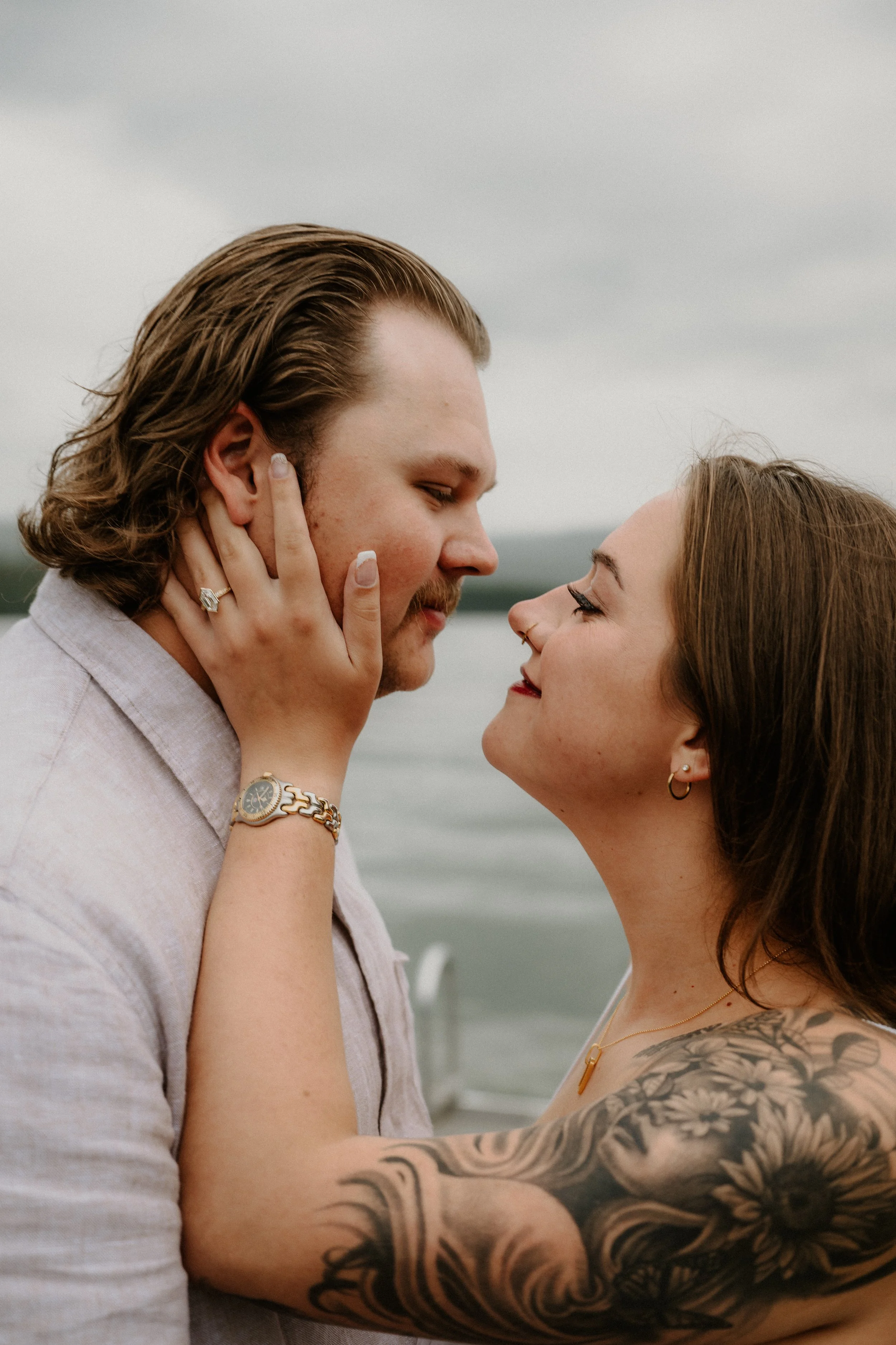 Newly engaged couple embracing in the rain on the Lake McDonald dock in Glacier National Park