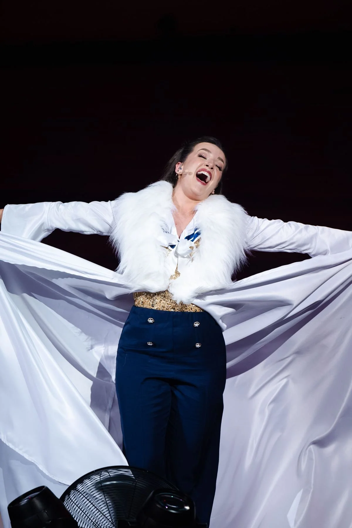 An artist of the House throwing open a white cape mid-song