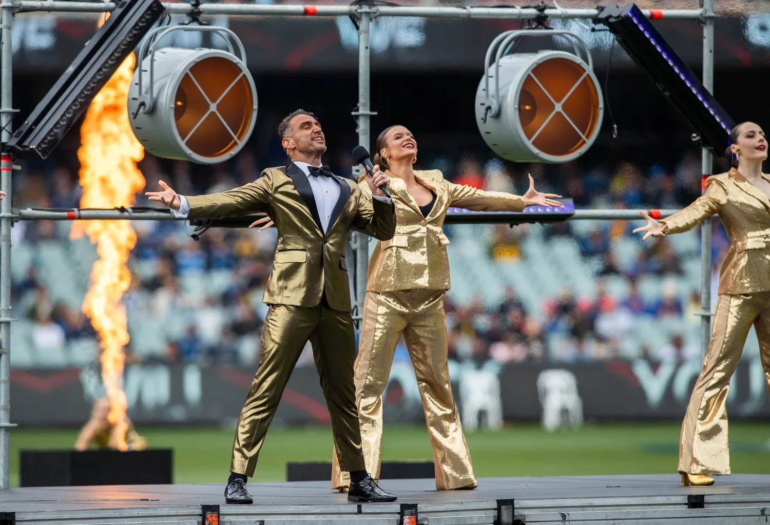 Dancers in gold with pyrotechnics in a stadium spectacular