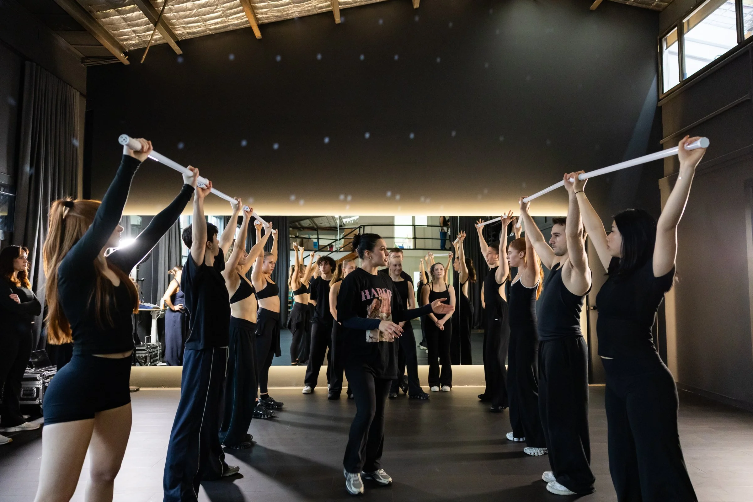 A full cast rehearsing choreography under warm studio light