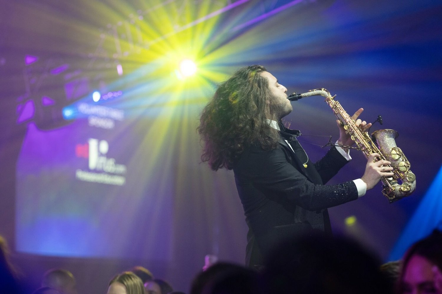 A saxophonist with a crystal saxophone under stage lights