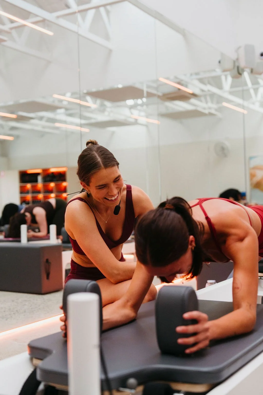 A trainer guiding a member on the reformer