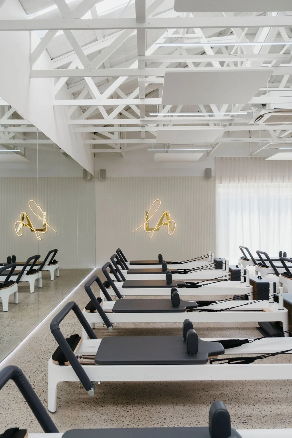 Light-filled Reformer studio with gold LA neon