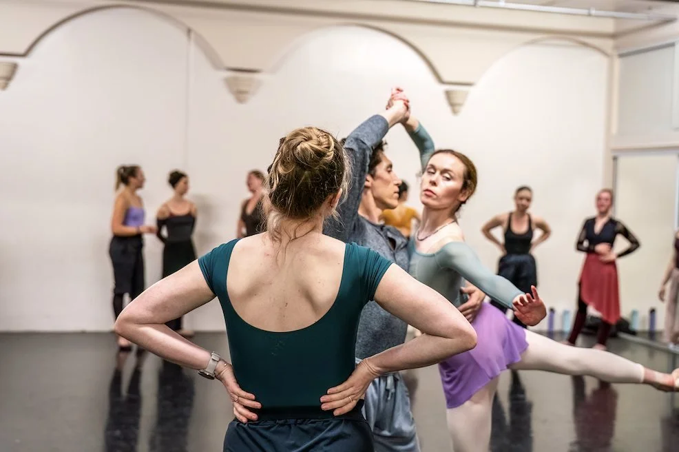 A ballet master watches two dancers rehearse in the studio.