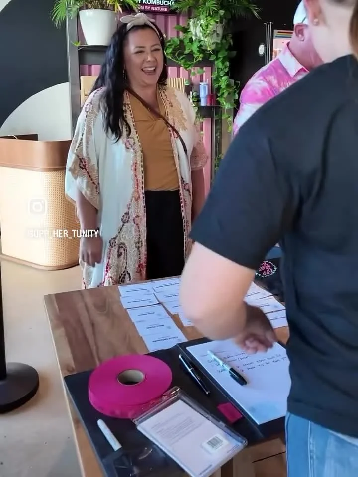A guest talking with attendees at the oppHERtunity sign-in table