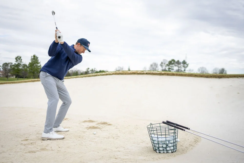 Golfer swinging from a bunker