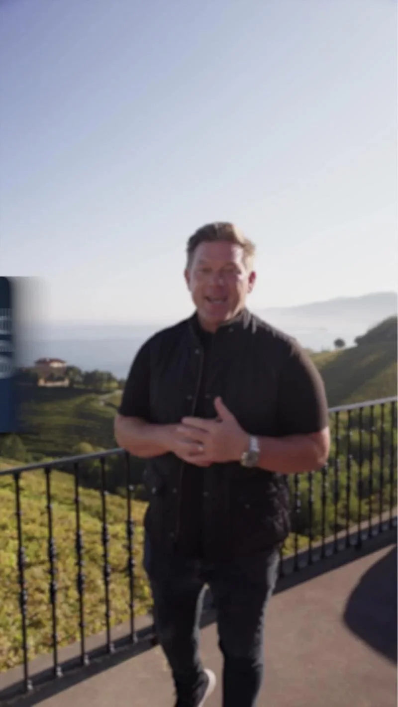Host speaking on a terrace overlooking the coast