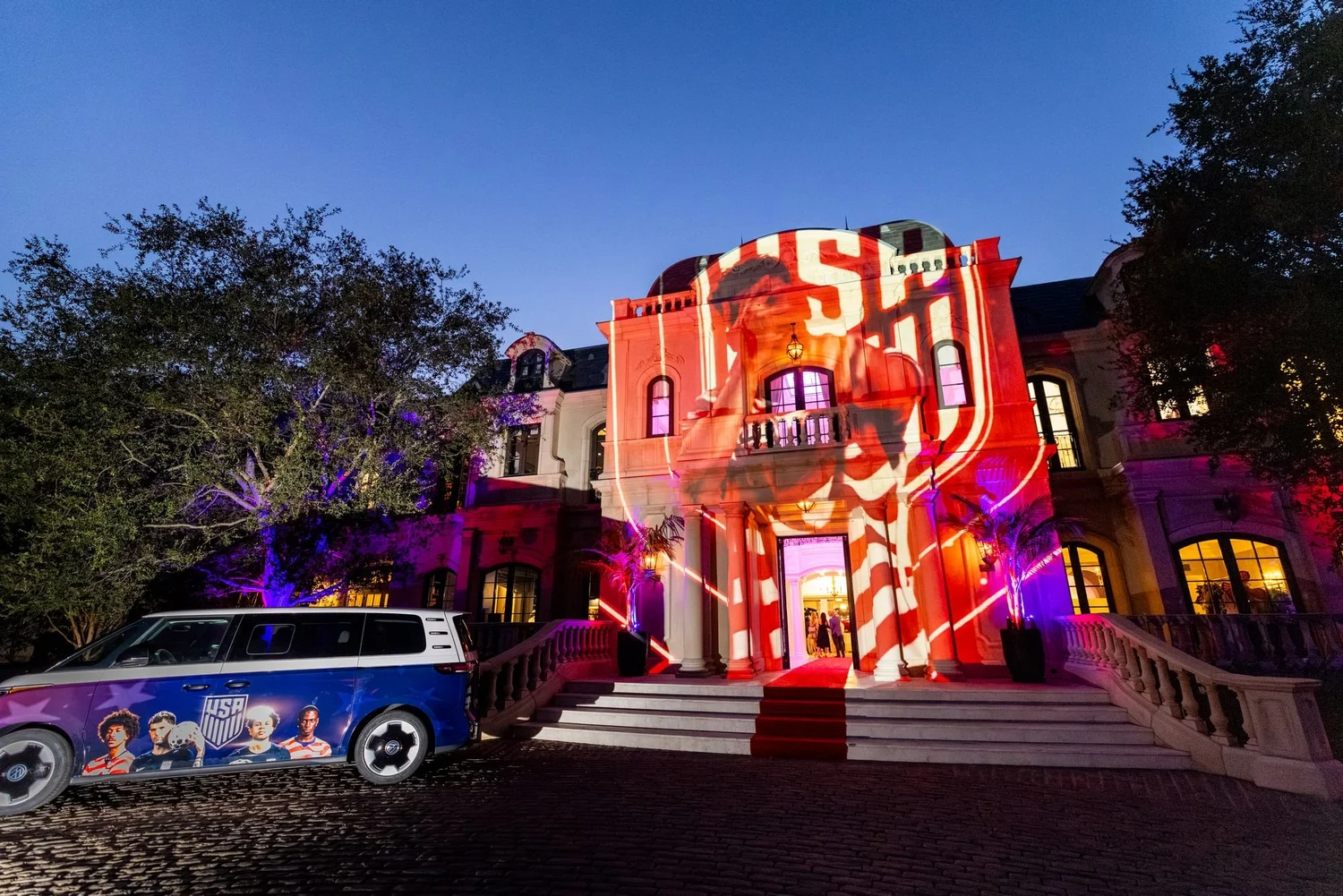 Estate lit up with brand projection at dusk